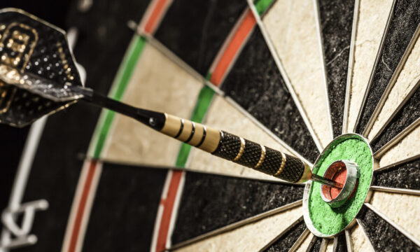 Success hitting target aim goal achievement concept background - dart in bull's eye close up